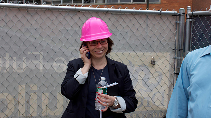 Anna Chrulkiewicz in pink hardhat outside the construction of LeBow Hall