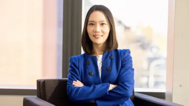 Headshot of Chen Wang, PhD, Associate Professor of Marketing sitting in chair in front of window