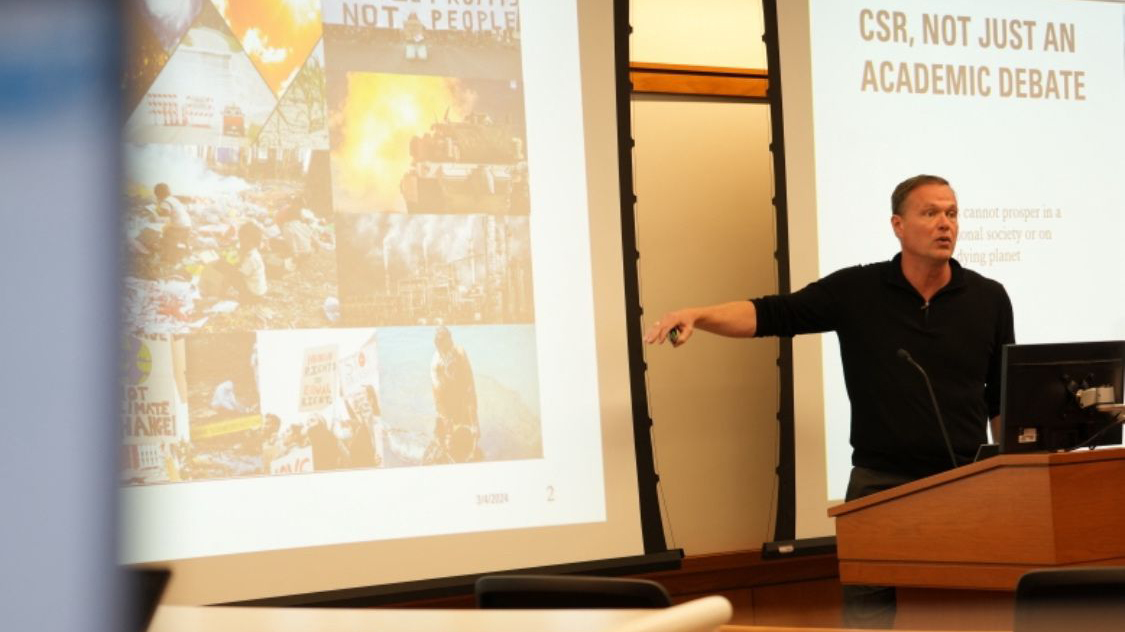Simon Nijnens pointing to a slide about his research on CSR