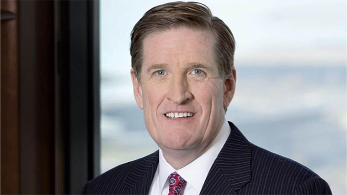 Man in black suit with part of red necktie visible at bottom center