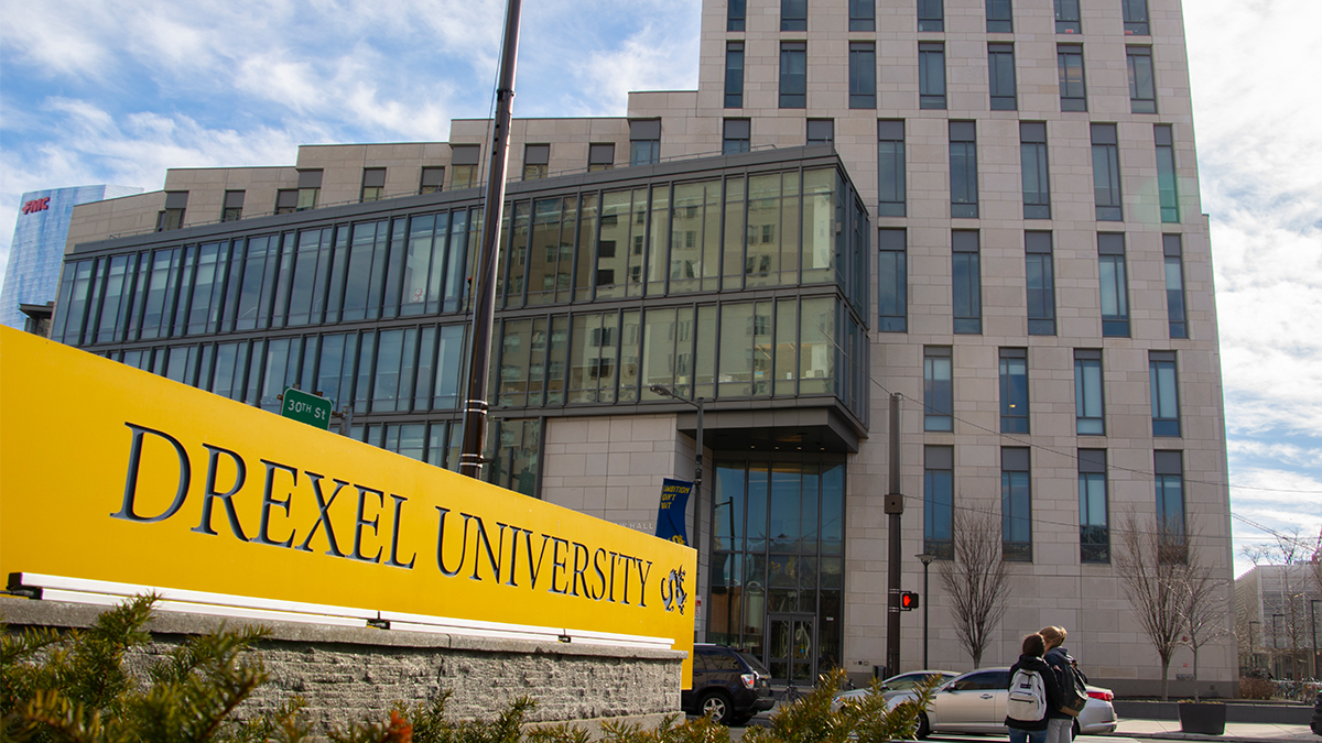 Gerri C. LeBow Hall, viewed from the north side of Market Street, with a yellow sign reading Drexel University visible