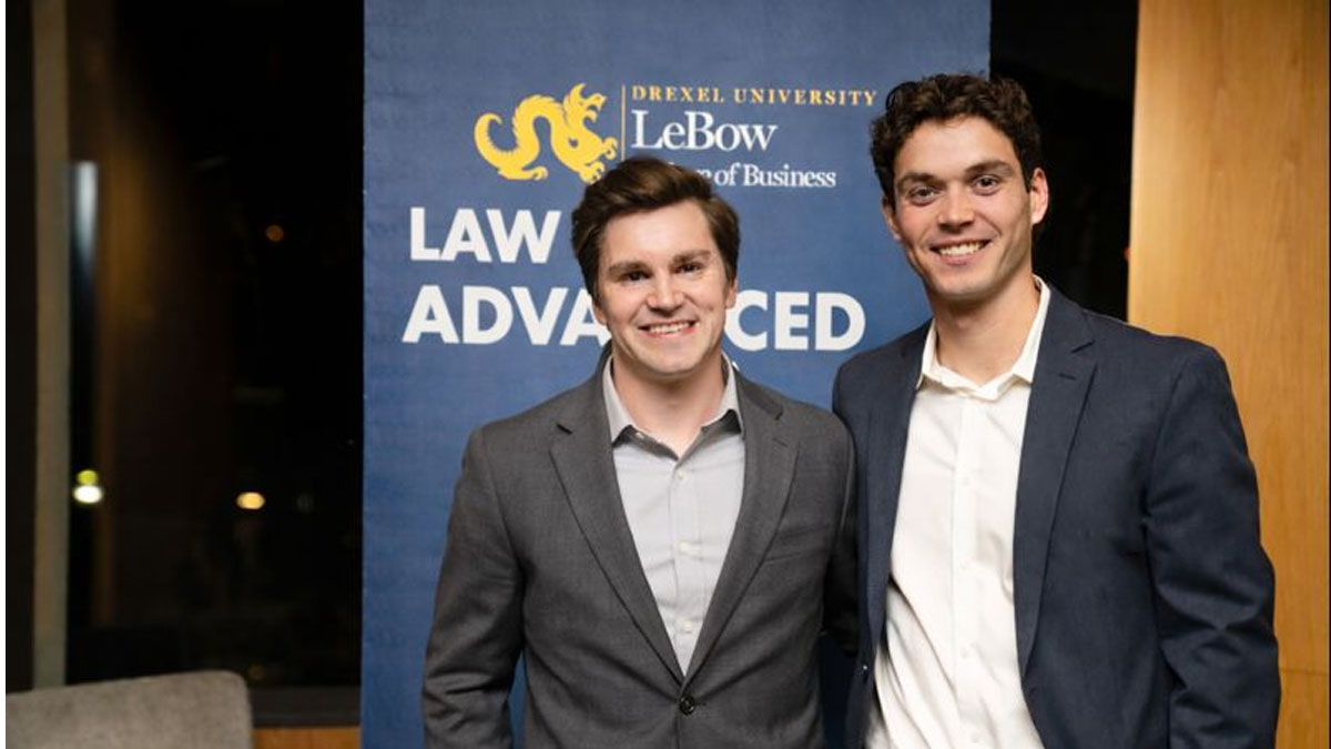 Two men in business attire in front of a blue backdrop with the LeBow College of Business logo visible at the top
