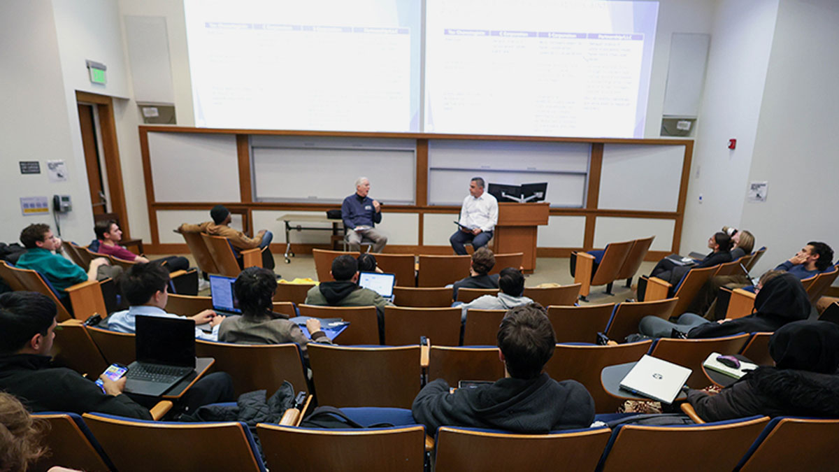 An undergraduate accounting classroom with professor and guest lecturer visible at the front of the room