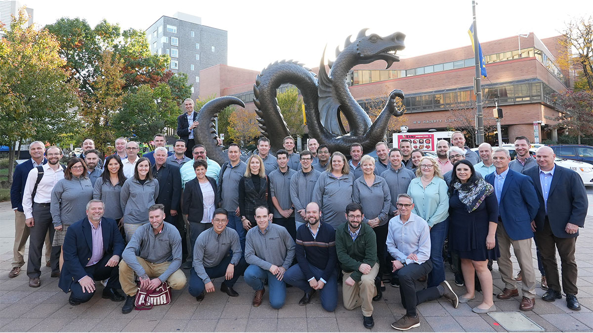 Group of people posing in front of large dragon sculpture.