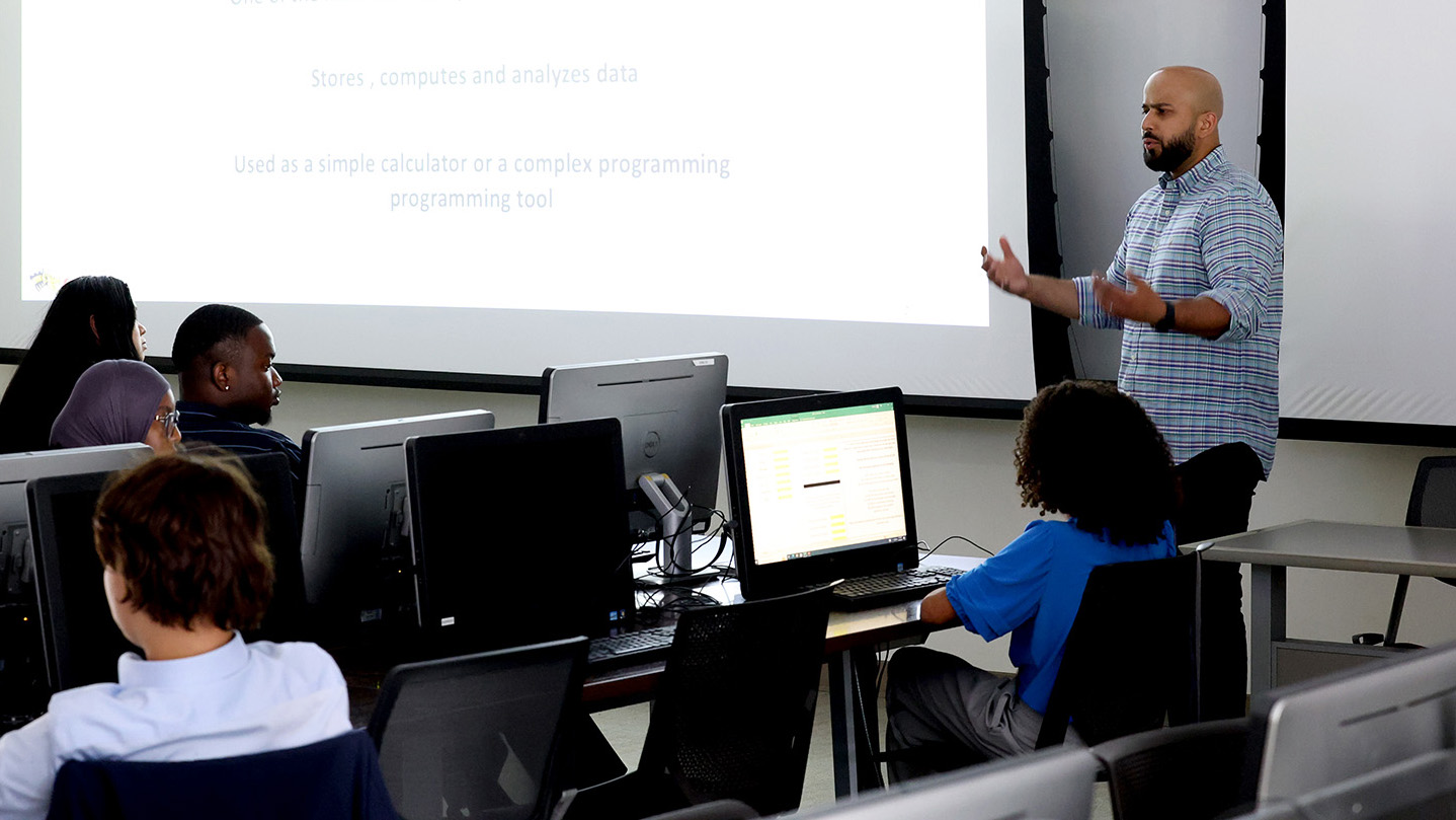 JT Thazhathel, assistant clinical professor of accounting, instructs students during the Accounting Finance Business Initiative summer program A professor teaches at the front of the classroom in front of a screen
