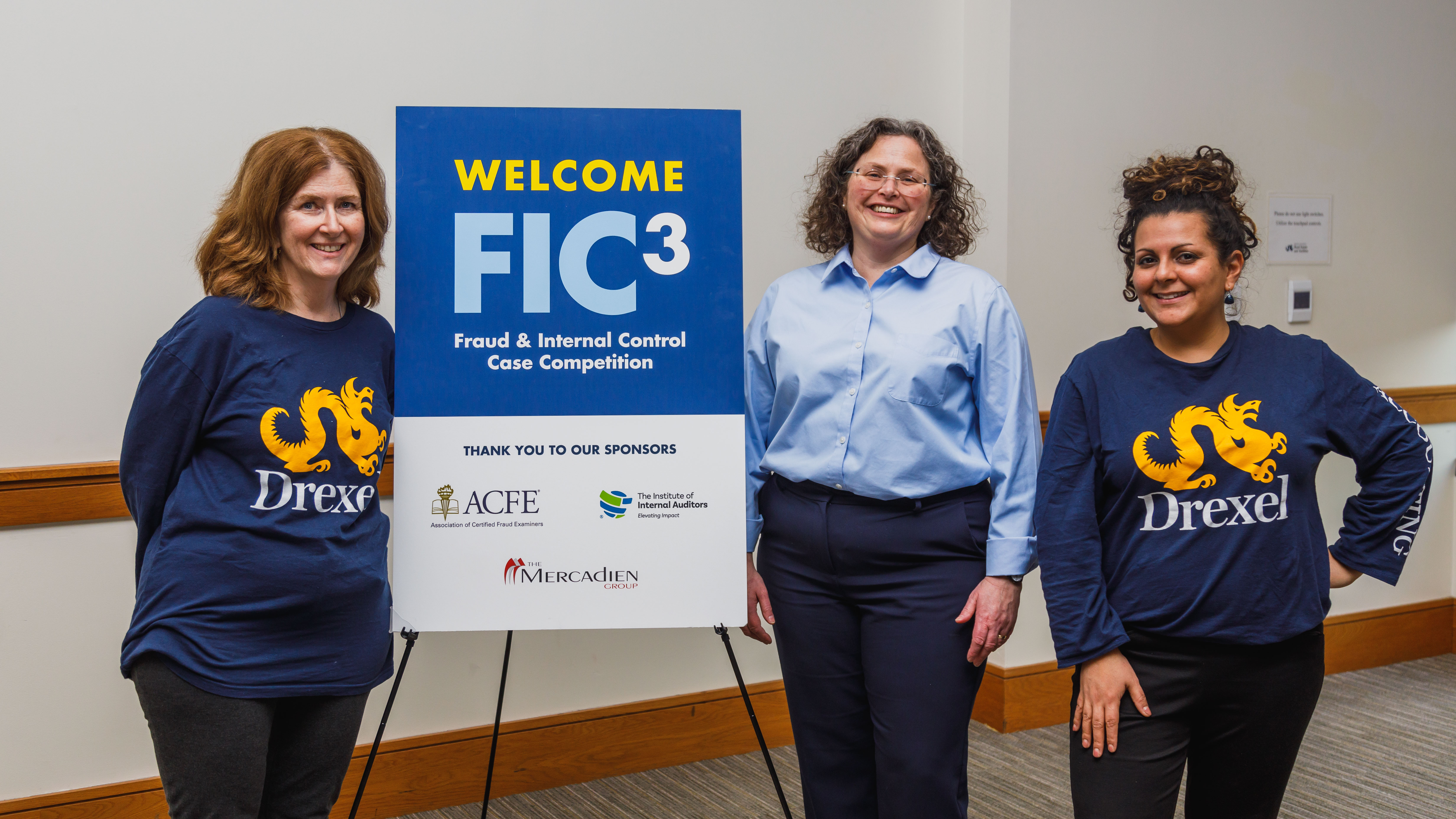 Barbara Grein, PhD, associate professor of accounting (center) Two women on the left and right wearing navy Drexel University t-shirts and one woman at center wearing a light blue dress shirt