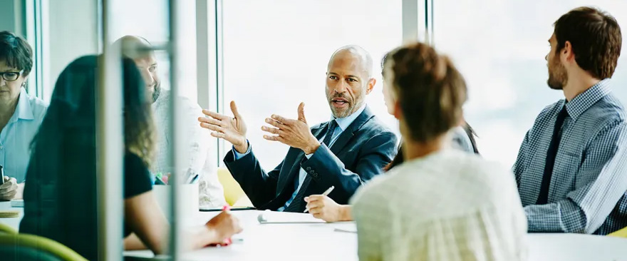 leader at a boardroom table discussing matters with the group