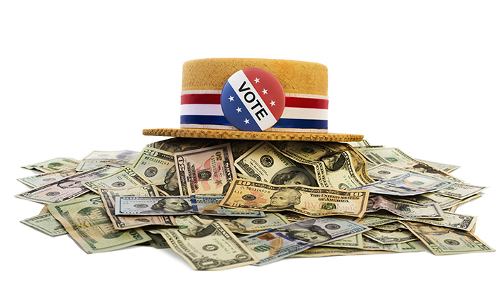 Vote button on hat sitting on a pile of money