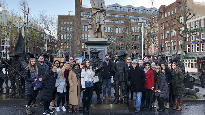 Amsterdam travels Students gather for a photo in front of a statue in Amsterdam