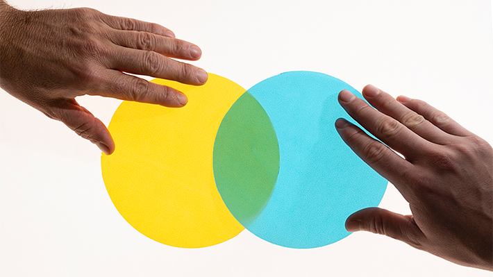 Two hands positioning yellow and blue circles into a Venn diagram