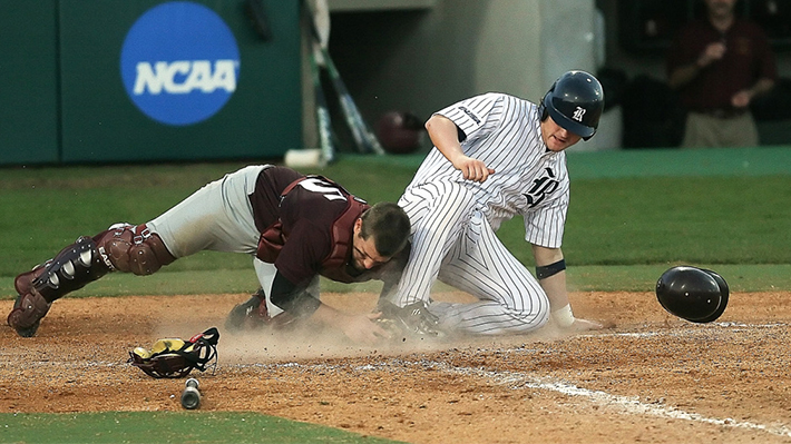 A baseball player slides into home plate near the opposing team's catcher