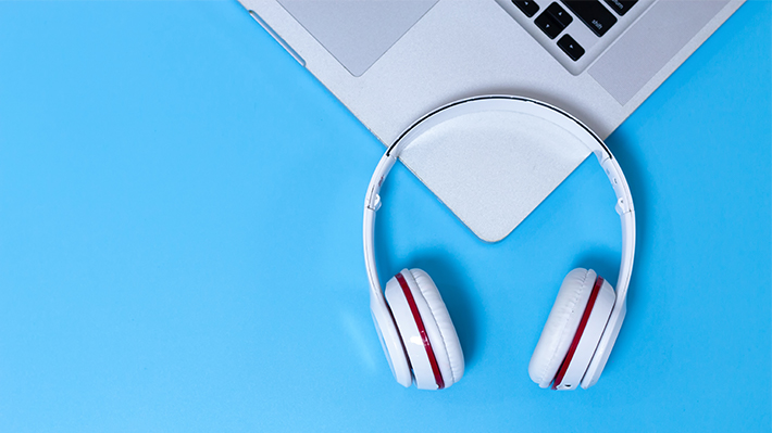 Headphones and laptop against a light blue background Headphones and laptop against a light blue background