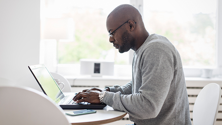 Side view of man using laptop on table at home Side view of man using laptop on table at home