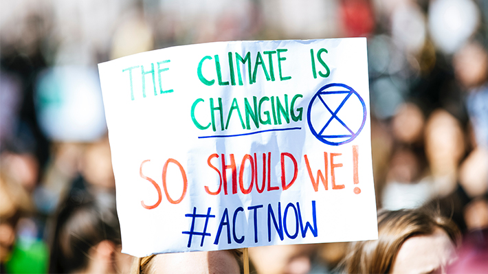 Sign at a protest reading "The climate is changing, so should we #ActNow"
