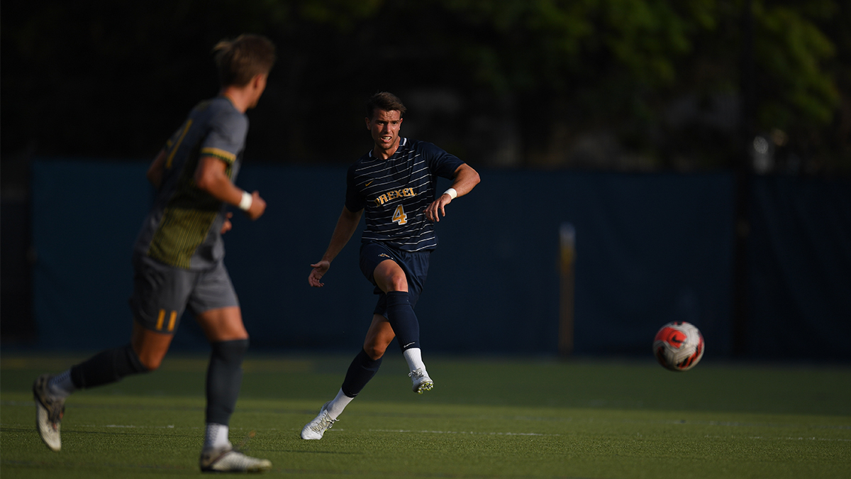 Daniel Nessler, MBA '23 (right) playing for the Drexel Dragons men's soccer team Two soccer players in uniform on the playing field