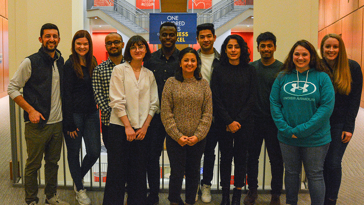 Eleven individuals, dressed casually, posed on the second floor of Gerri C. LeBow Hall