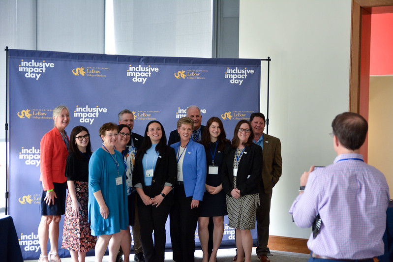 Attendees pose in front of Inclusive Impact Day banner
