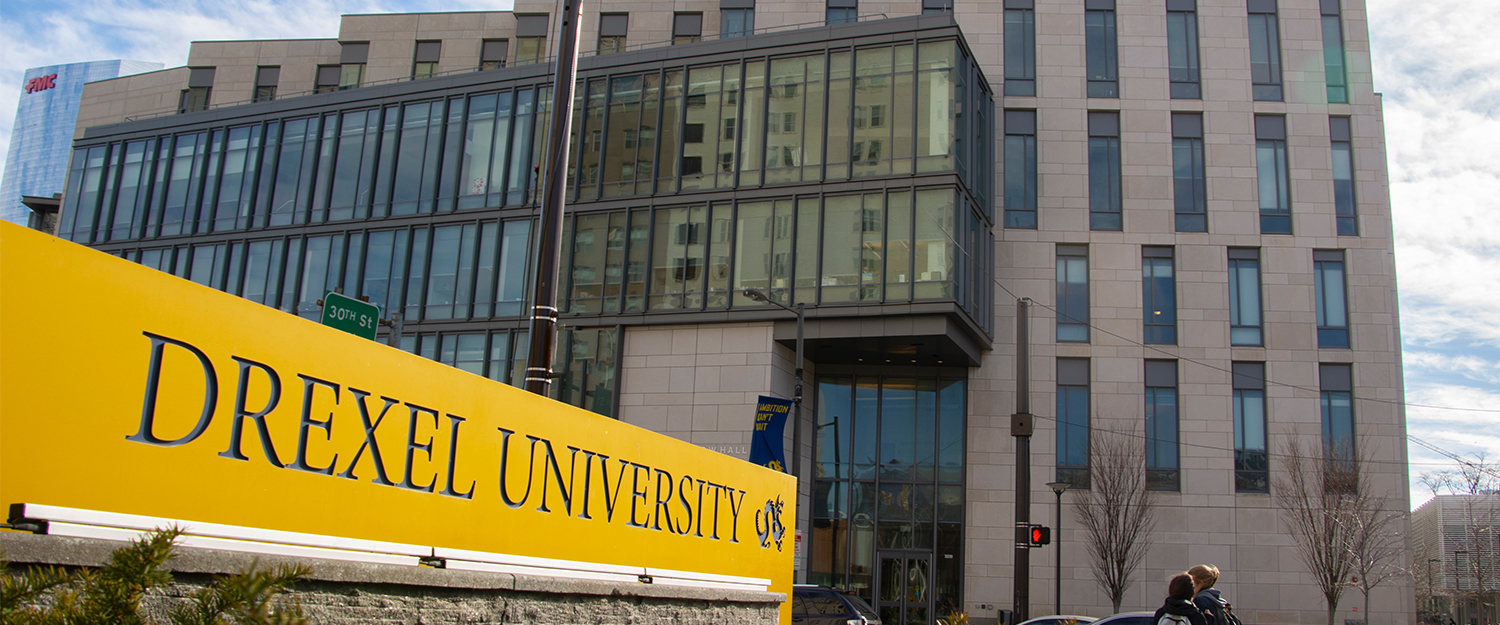 Gerri C. LeBow Hall, viewed from the north side of Market Street, with a yellow sign reading Drexel University visible