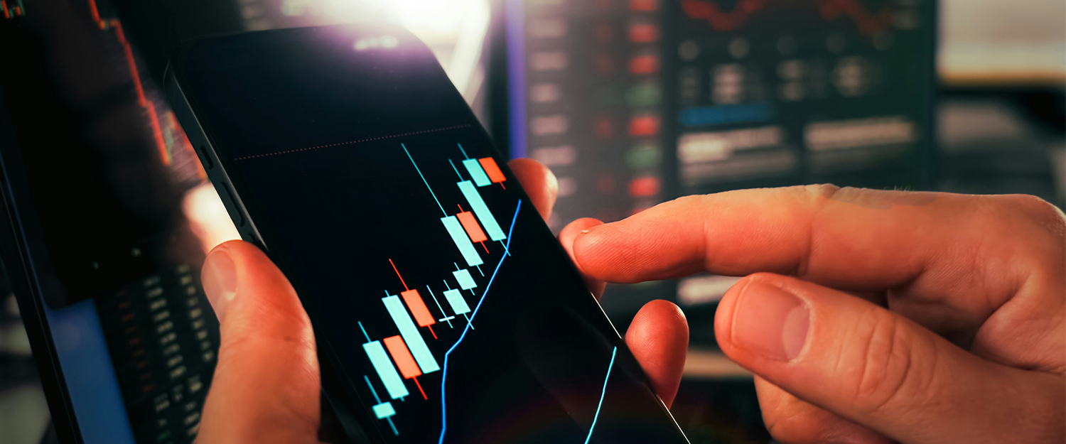 Financial data visible on the screen of a smartphone with a hand with index finger extended pointing toward it