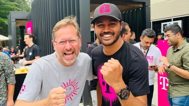 Two men smiling and making a fist-pumping gesture outdoors