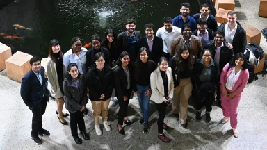 A group of students standing in front of an indoor koi pond