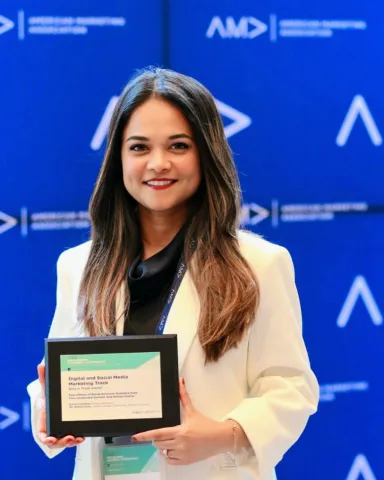 Woman wearing white blazer standing in front of a blue wall holding a plaque