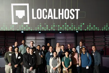 A group of men and women under a sign reading Localhost with the company's logo