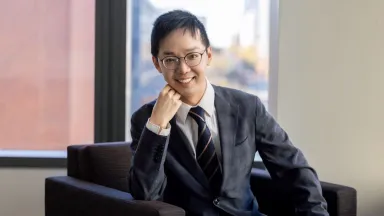 Landscape portrait of Dan Dai, PhD, Assistant Professor, Accounting sitting in chair with right arm under chin