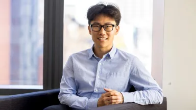 Headshot of Chuck Fang, PhD, Assistant Professor of Finance sitting in chair by window