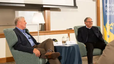 Two men seated with a table in between them