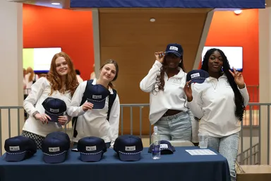 Drexel LeBow students wear branded sweatshirts and hand out free hats during Welcome Week.