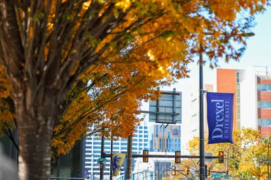 Beautiful fall foliage on Drexel's Philadelphia campus with a Drexel University banner in the background.