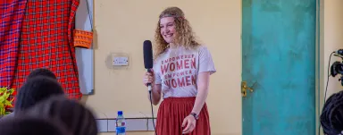 A woman presents to a group wearing a shirt that reads Empowered Women Empower Women.