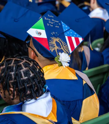 The top of a graduation cap with images of the Mexican and United States flags and a short text written in Spanish in the middle