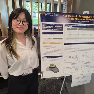 Student poses with a whiteboard explainer for research screated as a STAR Scholar at Drexel LeBow.