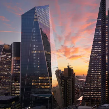 City skyscrapers at sunset with vibrant pink and orange clouds.