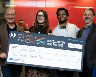 The Charles D. Close School of Entrepreneurship leadership pose with StartUp Fest 2025 winners and their $10,000 prize check, which will be used to fund their startup.