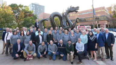 Group of people posing in front of large dragon sculpture.