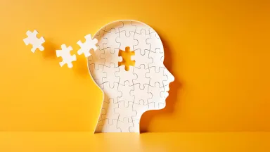 White jigsaw silhouette head with missing pieces on orange background.