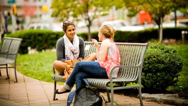 Two Drexel LeBow students talking on a bench outside