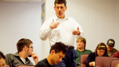 Man teaches in front of classroom as students look on