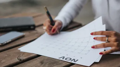 Woman writing on a calendar with her smartphone next to her