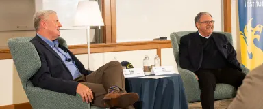 Two men seated with a table in between them