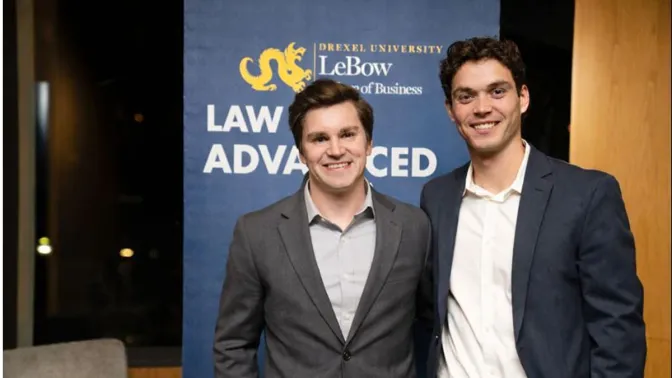Two men in business attire in front of a blue backdrop with the LeBow College of Business logo visible at the top
