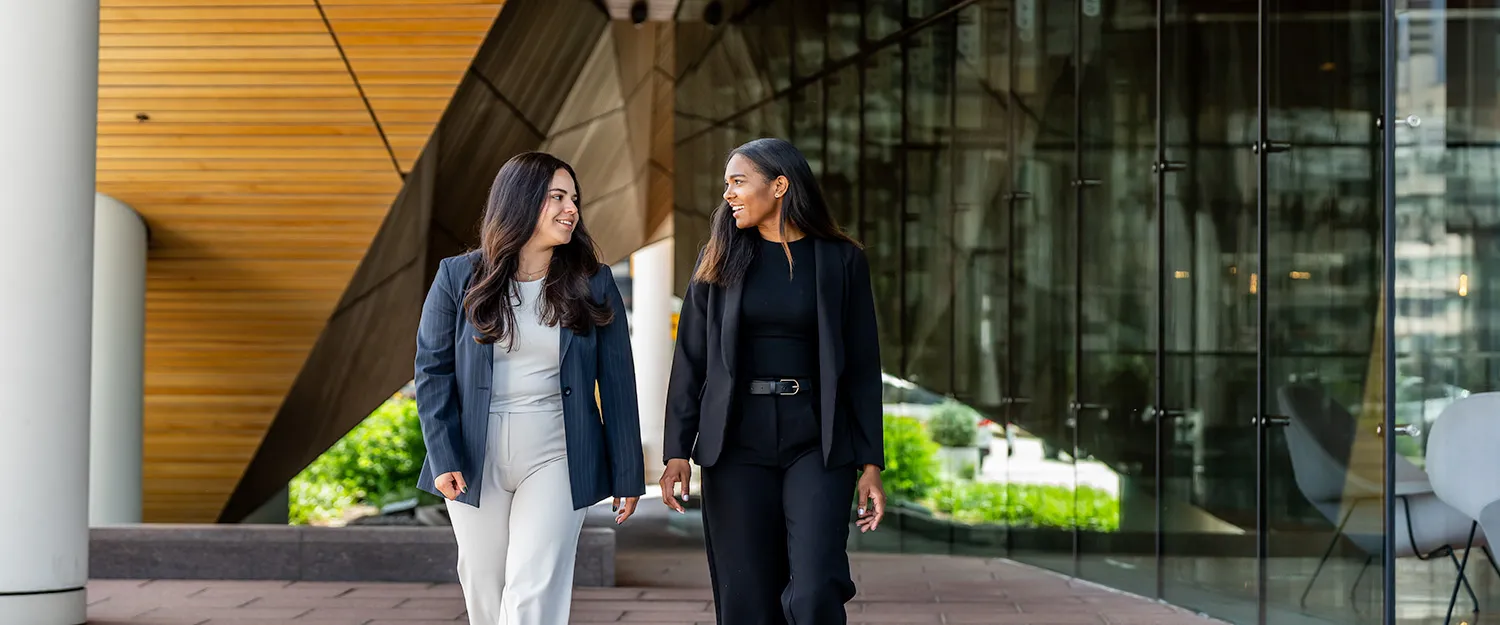 Two professional looking students stroll on Drexel's campus, discussing classwork