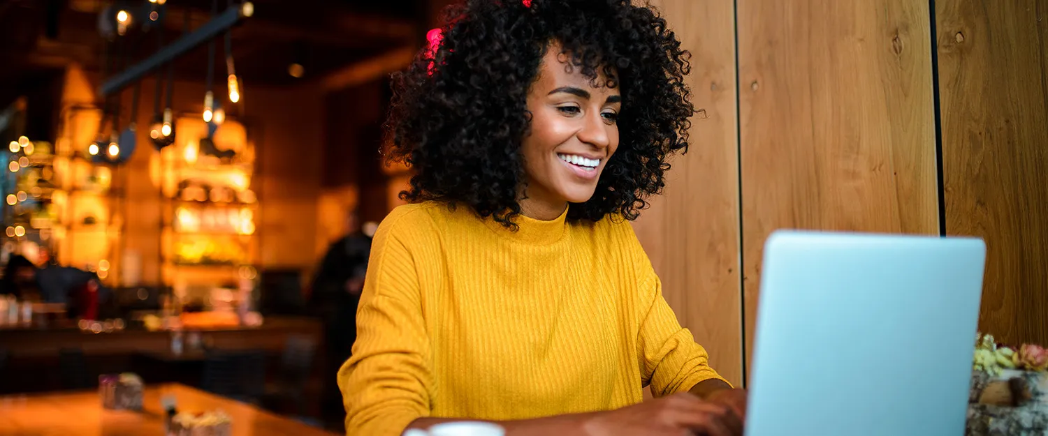 a woman smiles at the screen while using her laptop to attend an Drexel LeBow online class.