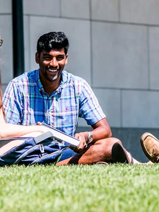 Drexel students sitting on the lawn in front of Gerri C. LeBow Hall