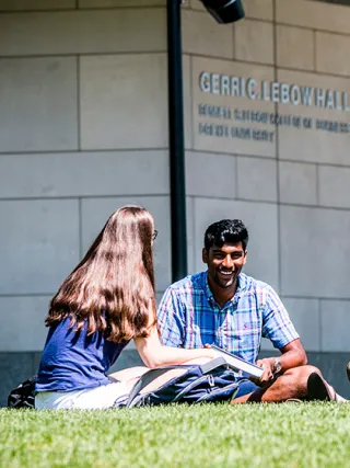 Drexel students sitting on the lawn in front of Gerri C. LeBow Hall