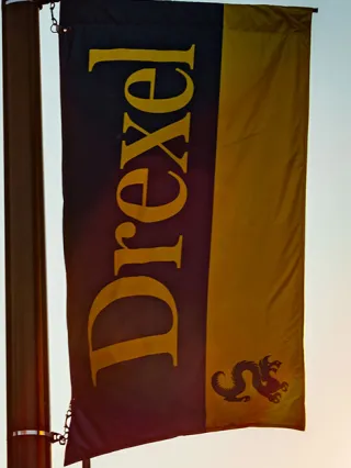 a drexel banner hangs outside LeBow as the sun sets
