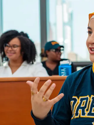 a student wears drexel colors and sweatshirt while having a discussion in class